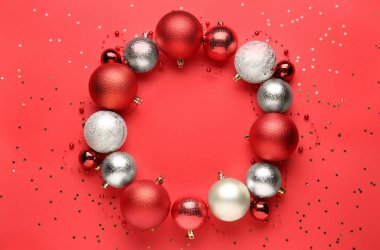 Kırmızı arka planda renkli Noel toplarından yapılmış güzel bir çelenk.