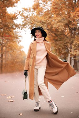 Şehir caddesinde şık kıyafetler giyen genç bir kadın. Sonbahar görünümü