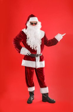 Kırmızı arka planda güneş gözlüklü Noel Baba 'nın tam boy portresi