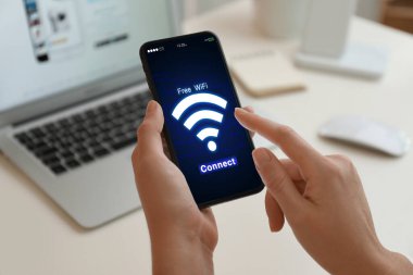 Wi-Fi 'a bağlanan kadın masadaki cep telefonunu kullanıyor, yakın plan