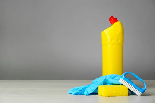 Bottle of cleaning product and supplies on light table. Space for text