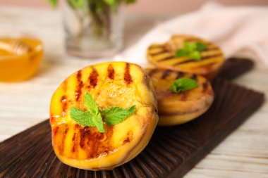 Ahşap tahtada naneli enfes ızgara şeftaliler, yakın plan.