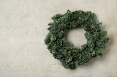 Açık gri zemin üzerinde köknar ağacı dallarından yapılmış Noel çelengi, metin için boşluk