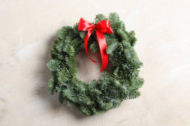 Noel çelengi köknar ağacı dallarından yapılmıştır. Arka planda kırmızı kurdele vardır.