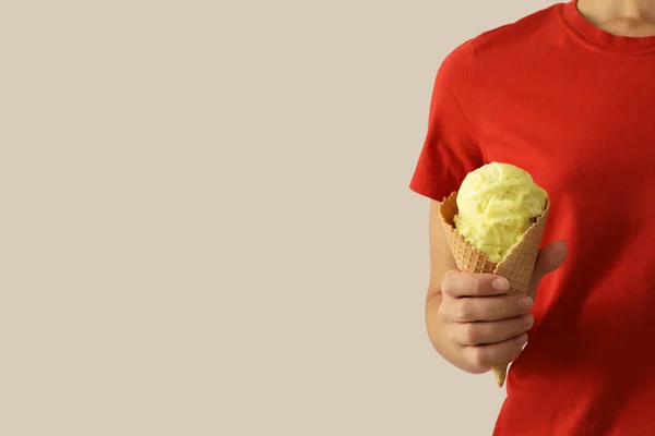 薄い灰色の背景に ウエハコーンに黄色のアイスクリームを保持する女性を閉じます テキストのスペース — ストック写真