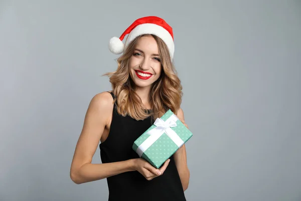 Happy Young Woman Wearing Santa Hat Christmas Gift Grey Background — Stock Photo, Image