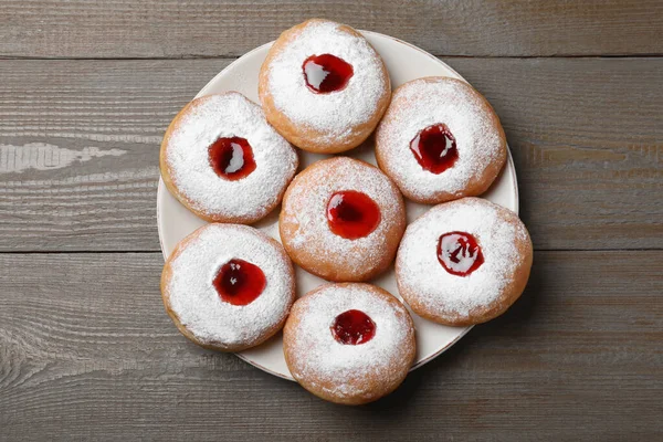 Hanukkah doughnuts with jelly and sugar powder served on wooden table, top view