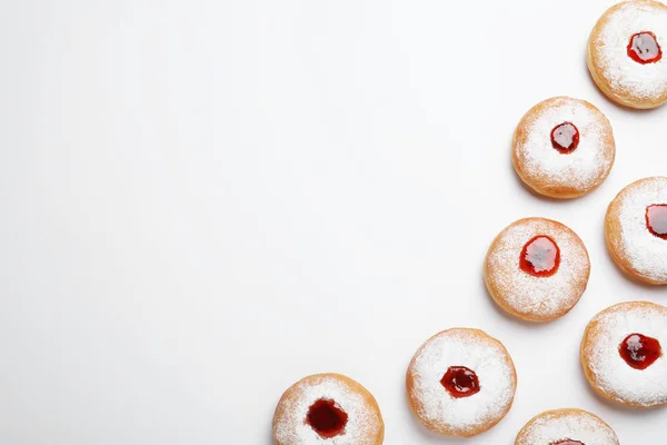 Hanukkah doughnuts with jelly and sugar powder on white background, top view. Space for text