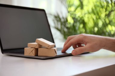 İnternet alışverişi. İçerideki masada dizüstü bilgisayar kullanan küçük kutular, yakın plan.