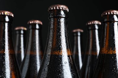 Siyah arka planda bira şişeleri, yakın plan.