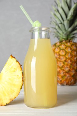 Lezzetli ananas suyu ve beyaz ahşap masada taze meyve.