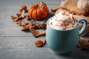Gri ahşap masada lezzetli balkabaklı latte, yakın plan.