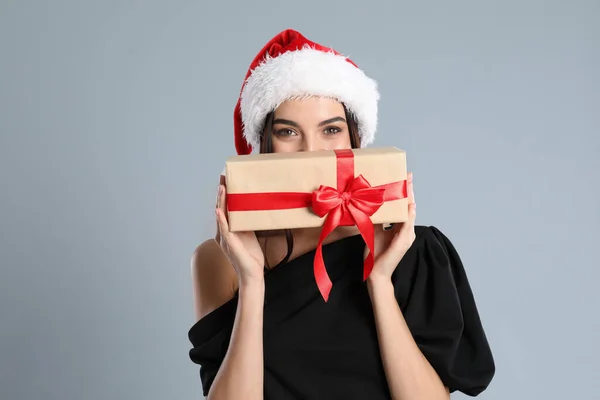 Mulher Vestido Preto Chapéu Santa Segurando Presente Natal Fundo Cinza — Fotografia de Stock