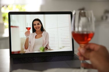 Mutfaktaki online video konferansında sohbet ederken şarap içen arkadaşlar. Koronavirüs salgını sırasında sosyal mesafeler