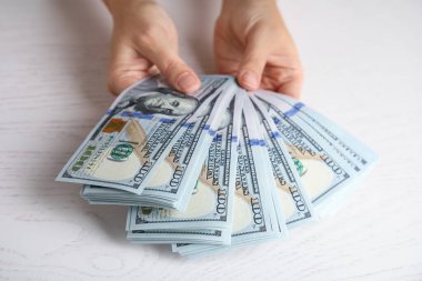 Beyaz ahşap masada elinde dolar banknotları tutan kadın.
