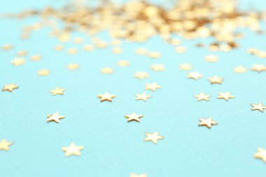 Açık mavi arka planda konfeti yıldızları, yakın plan. Noel kutlaması