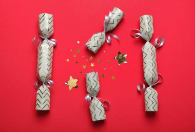 Kırmızı arka planda parlak konfetileri olan açık ve kapalı Noel krakerleri.