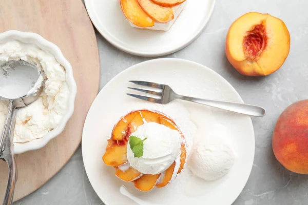 Delicious peach dessert with ice cream on light marble table, flat lay