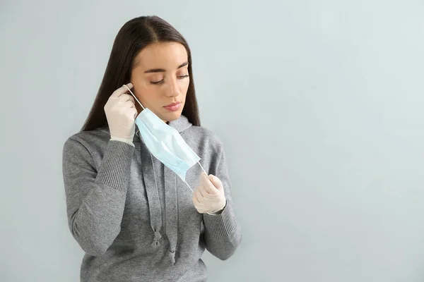 Mujer Con Guantes Médicos Poniéndose Mascarilla Protectora Contra Fondo Gris — Foto de Stock