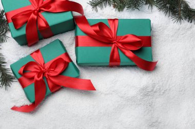 Hediye kutuları, Noel ağacı dalları ve yapay karla bezenmiş düz bir kompozisyon.