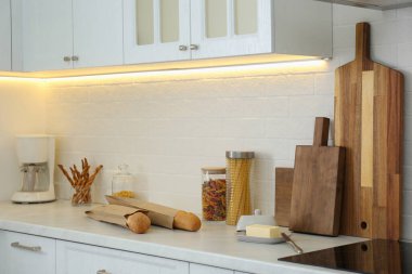 Modern kahve makinesiyle tezgah, ahşap kesim tahtaları ve şık mutfakta ürünler.