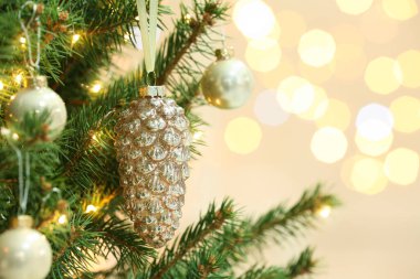 Cone shaped holiday bauble hanging on Christmas tree against blurred lights, closeup. Space for text clipart
