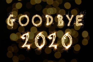 Hoşça kal 2020. Siyah arkaplandaki bulanık ışıklarla maytaptan yapılmış parlak metin