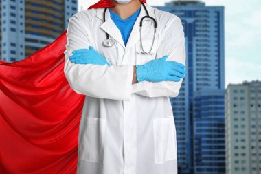 Şehir arka planında süper kahraman gibi giyinmiş bir doktor, yakın plan. Sağlık çalışanları tehlikeli hastalıklarla savaşıyor.