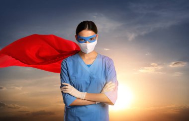 Sağlık çalışanları tehlikeli hastalıklarla savaşıyor. Gökyüzüne karşı poz veren süper kahraman kılığındaki doktor.