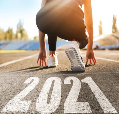 Yeni yıla yeni vizyon ve fikirlerle başla. Sportif kadın 2021 numaraya yakın koşmaya hazır, yakın plan.
