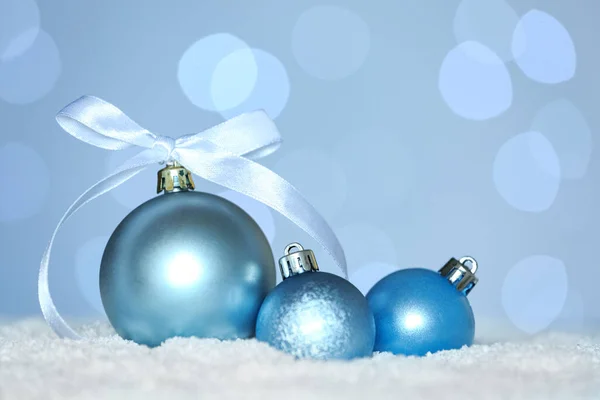 Schöne Hellblaue Weihnachtskugeln Auf Schnee Gegen Verschwommenes Festliches Licht — Stockfoto