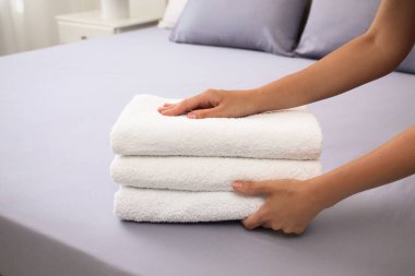 Kadın yatağa tereyağlı havlu koyuyor, yakın plan.