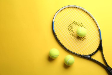 Tenis raketi ve toplar sarı arka planda, düz yerde. Metin için boşluk