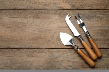 Peynir bıçakları ve çatal tahta masaya, düz yatar. Metin için boşluk