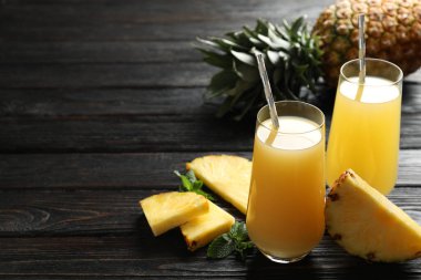 Lezzetli ananas suyu ve siyah ahşap masada taze meyve. Metin için boşluk