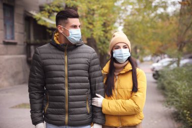 Dışarıda dolaşan tıbbi maskeli ve eldivenli bir çift. COVID-19 salgını sırasında kişisel koruma