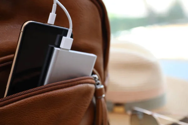 Charging mobile phone with power bank in backpack, closeup. Space for text