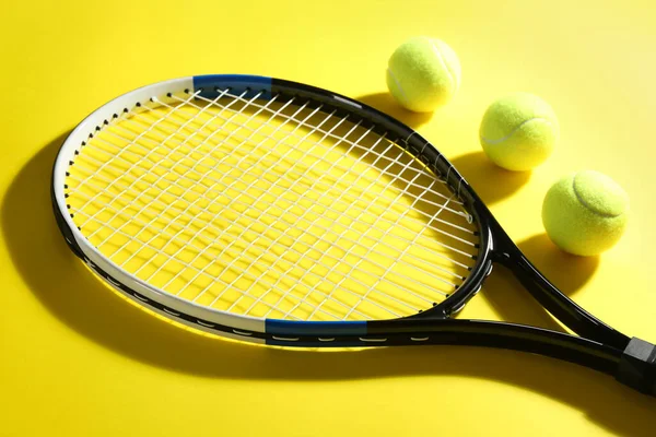 Tennis racket and balls on yellow background. Sports equipment