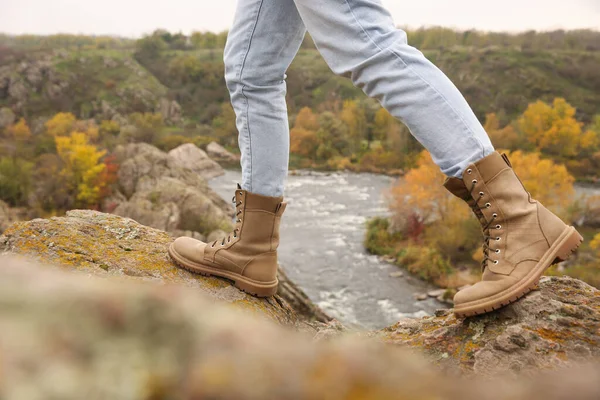 Woman wearing stylish hiking boots on steep cliff, closeup