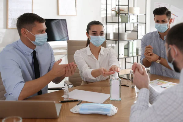 Compañeros Trabajo Con Máscaras Protectoras Usando Desinfectante Manos Oficina Reunión — Foto de Stock