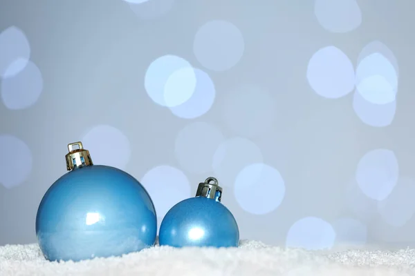 Schöne Hellblaue Weihnachtskugeln Auf Schnee Gegen Verschwommenes Festliches Licht Raum — Stockfoto