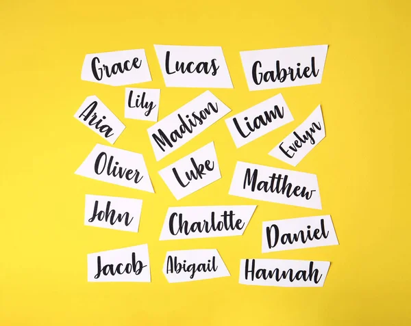 Folhas Papel Com Nomes Bebê Diferentes Escritos Fundo Amarelo Flat — Fotografia de Stock