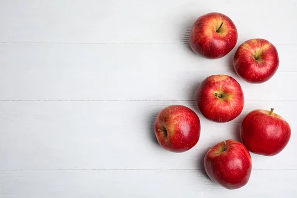 Ripe red apples on white wooden table, flat lay. Space for text