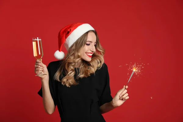 Kırmızı Arka Planda Bir Bardak Şampanya Maytapla Noel Baba Şapkası — Stok fotoğraf