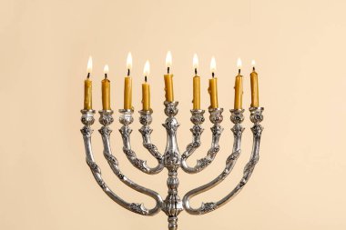 Bej arka planda yanan mumları olan gümüş menorah. Hanuka kutlaması