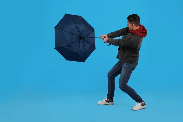 Человек Зонтиком Пойман Порывом Ветра Светло Голубом Фоне — стоковое фото