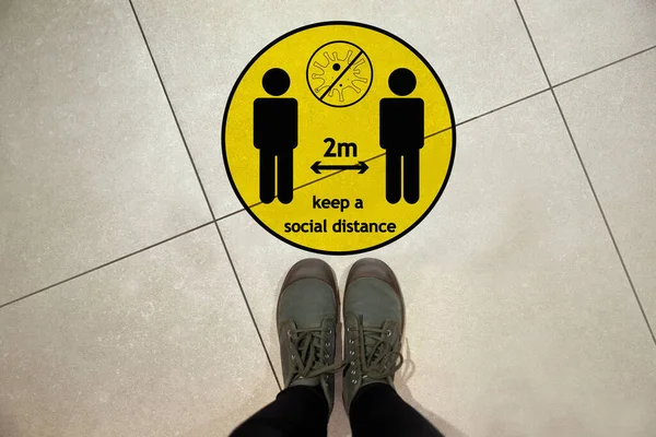 在大肠病毒爆发时保持社会距离作为预防措施 女性前地板上的黄色警示牌 — 图库照片