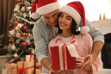 Noel Baba şapkalı mutlu çift evde Noel hediyesiyle