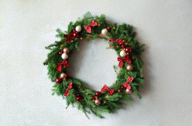 Beyaz duvarında şenlik süsleri olan güzel bir Noel çelengi