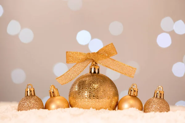 Schöne Goldene Weihnachtskugeln Auf Schnee Gegen Verschwommenes Festliches Licht — Stockfoto